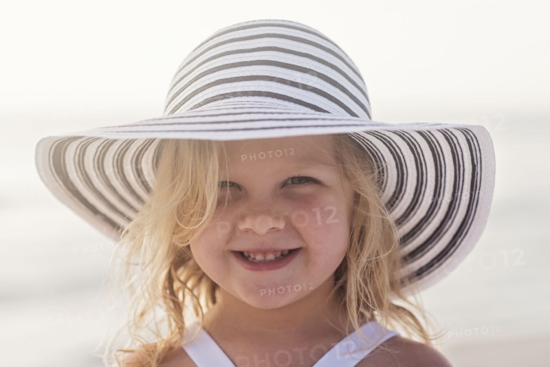 Portrait of girl (4-5) in sunhat at beach