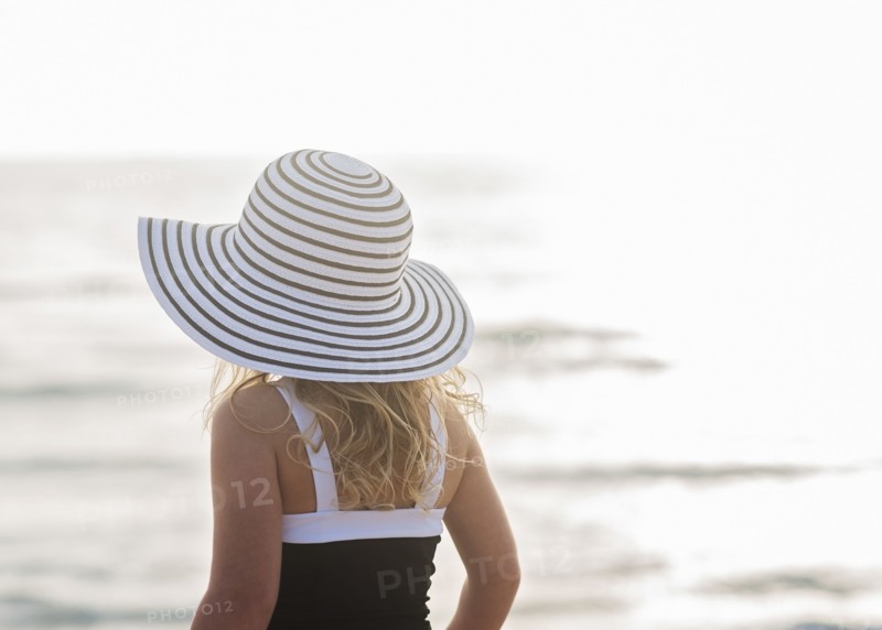 Girl (4-5) in striped sunhat by sea