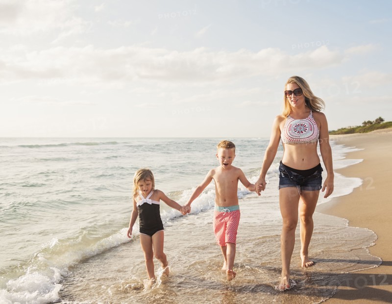 Mother walking with boy (6-7) and girl (4-5) on beach by water