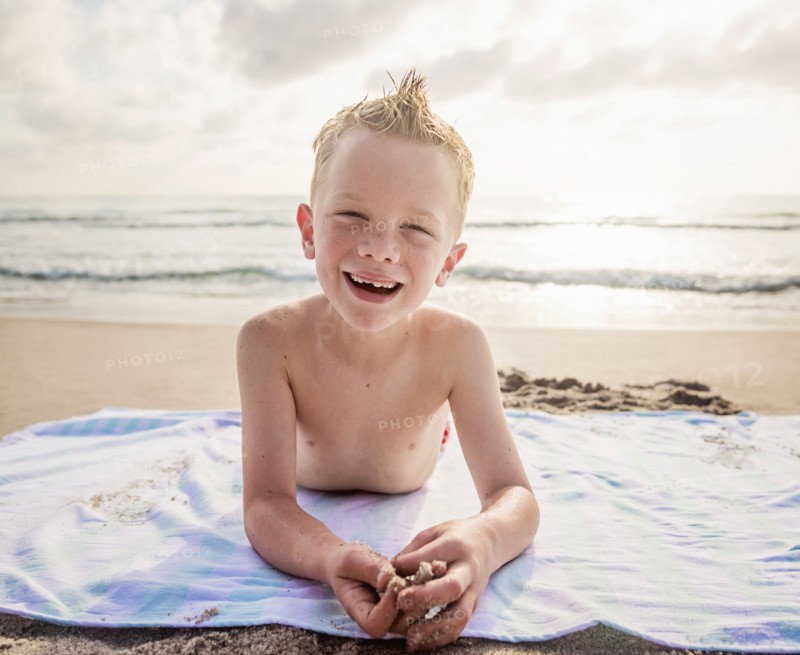 Portrait of boy (6-7) and girl (4-5) lying on beach laughing