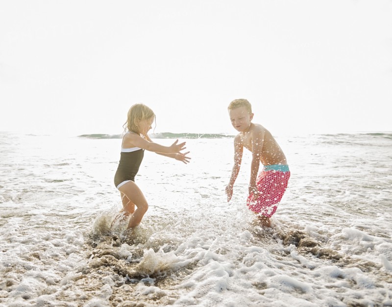 Mother walking with boy (6-7) and girl (4-5) on beach by water