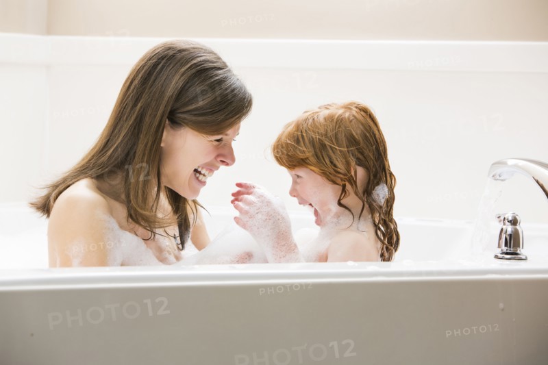 Mother and daughter (4-5) having bubble bath