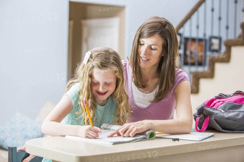 Mother and daughter (8-9) sitting at table doing homework