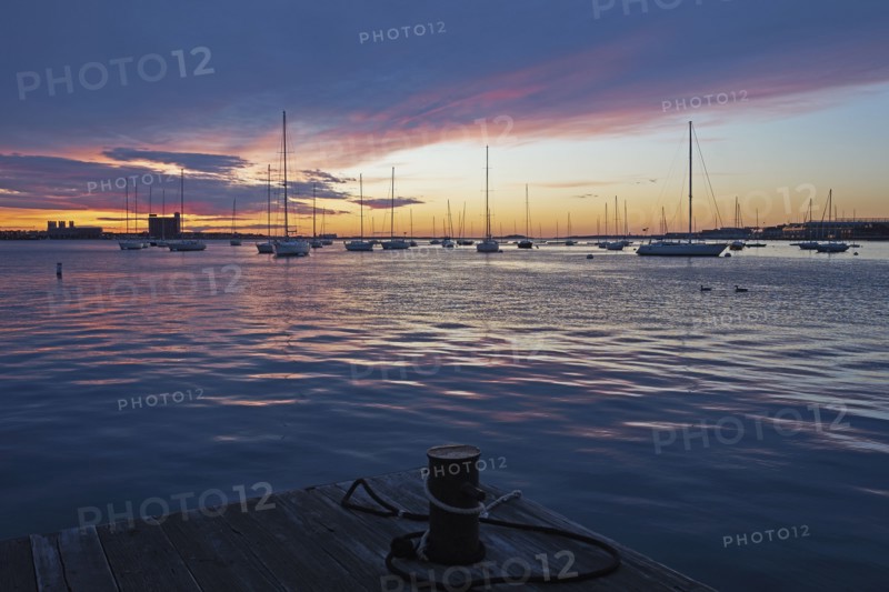 Boats moored in harbor at dawn