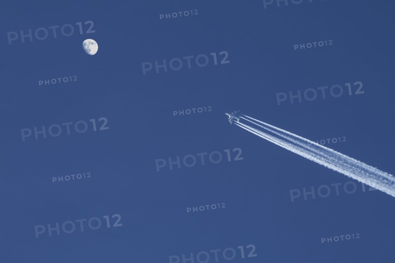 Airplane against blue sky with moon