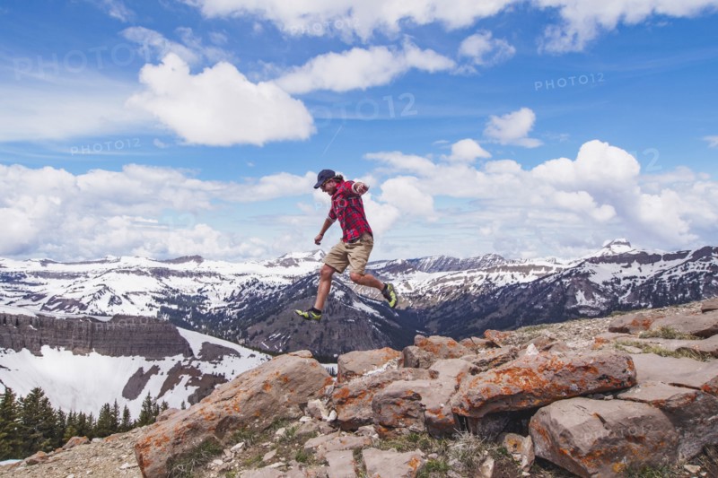 Mid adult man jumping over rocks in mountains