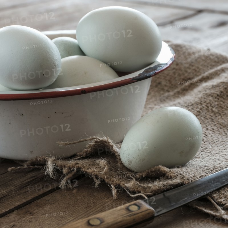Fresh eggs in bowl on wooden table.