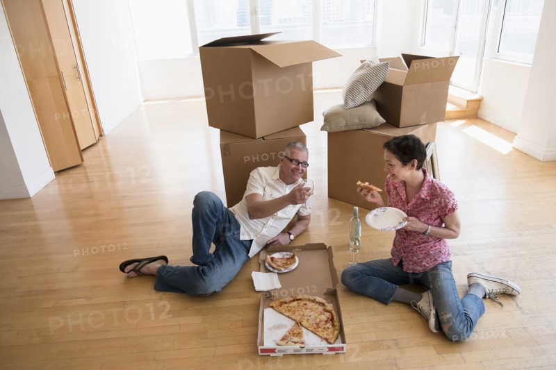 Couple eating pizza in new apartment.