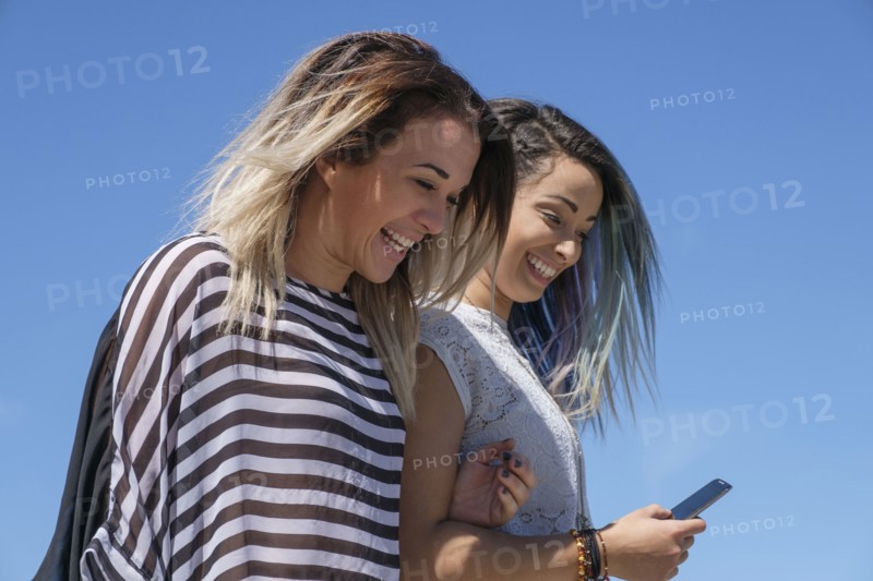 Young women laughing and looking at mobile phone.