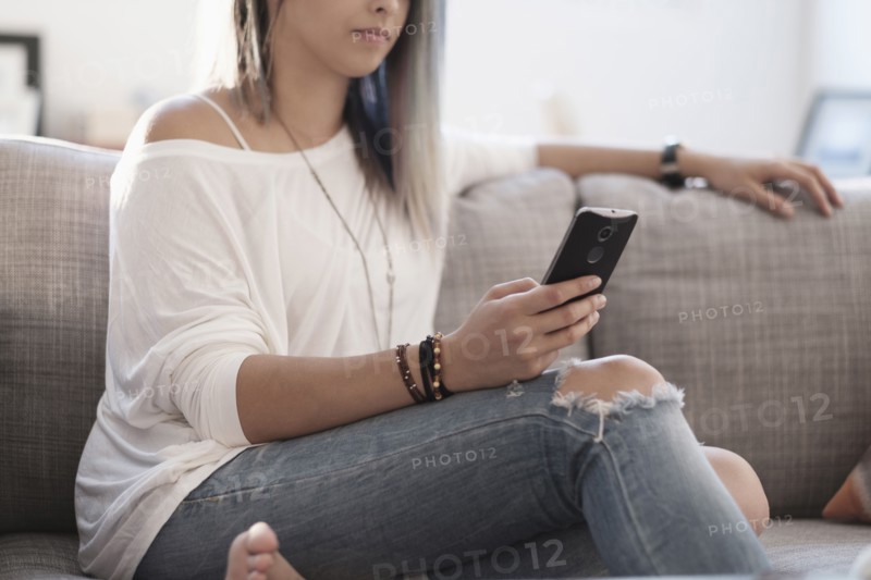 Young woman using mobile phone at home.