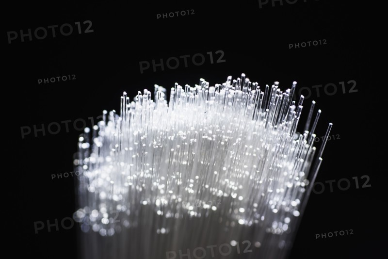 Bunch of glowing fiber optic cables on black background.