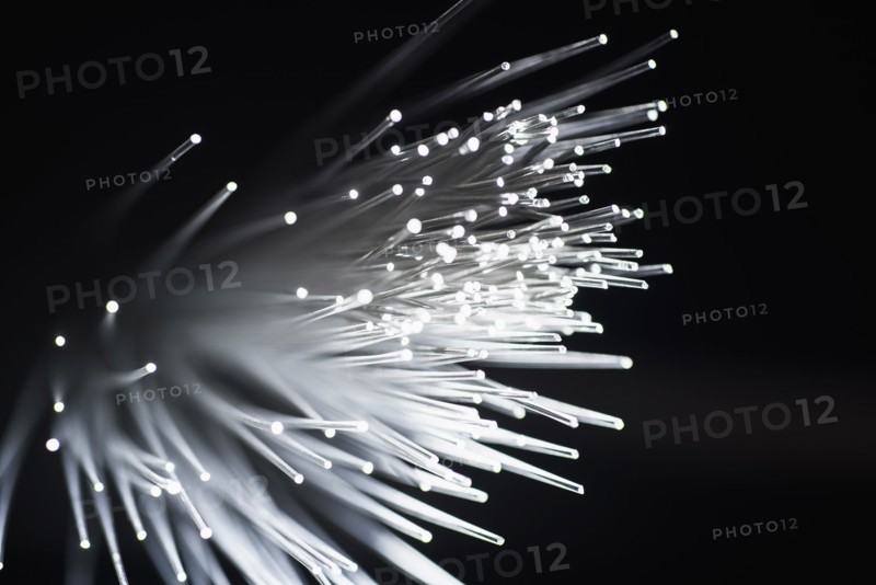 Bunch of glowing fiber optic cables on black background.