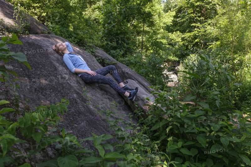 Woman lying on stone in forest.