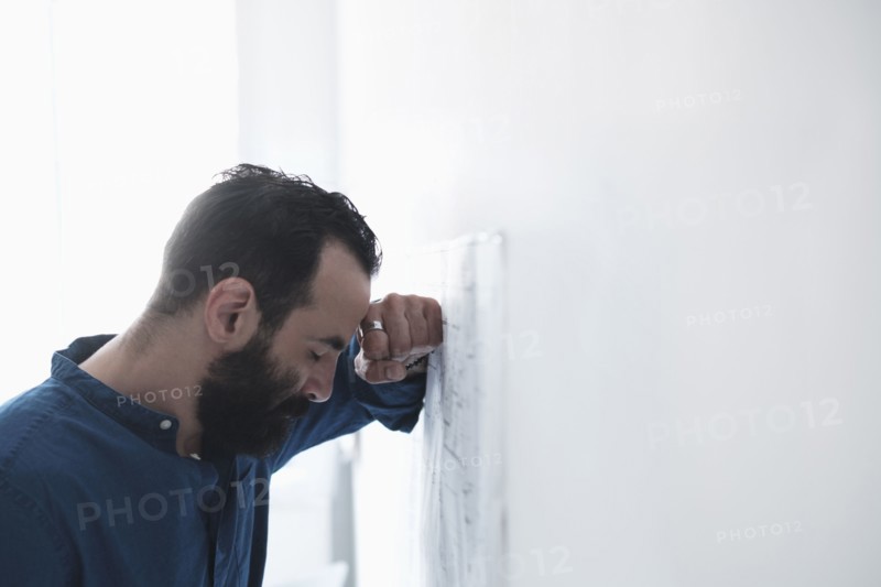 Tired man leaning by wall.