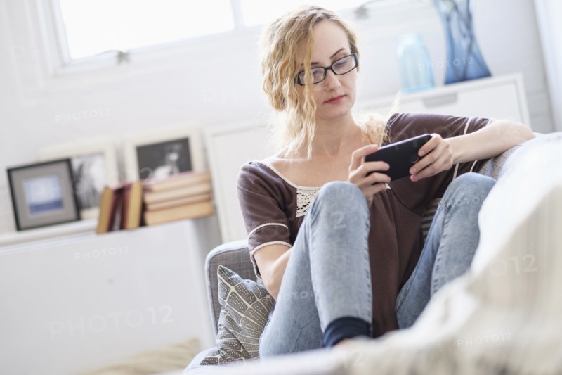 Woman sitting on sofa and using mobile phone.