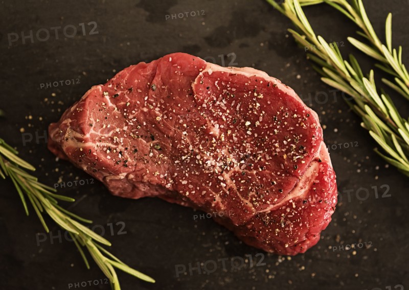 Steak between rosemary on tablecloth
