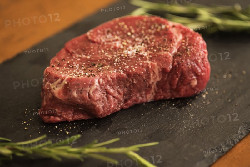 Steak between rosemary on tablecloth