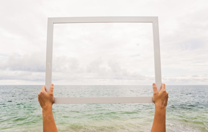 Person holding frame against cloudy sky