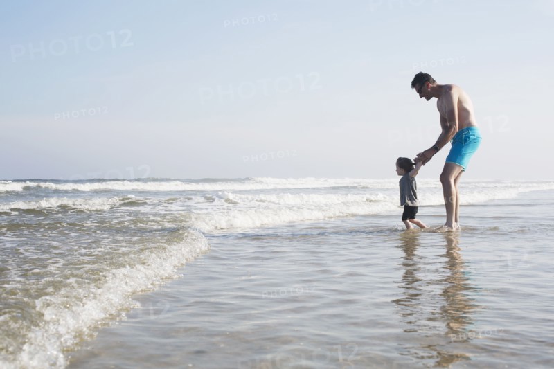Father with daughter (18-23 months) wading in sea