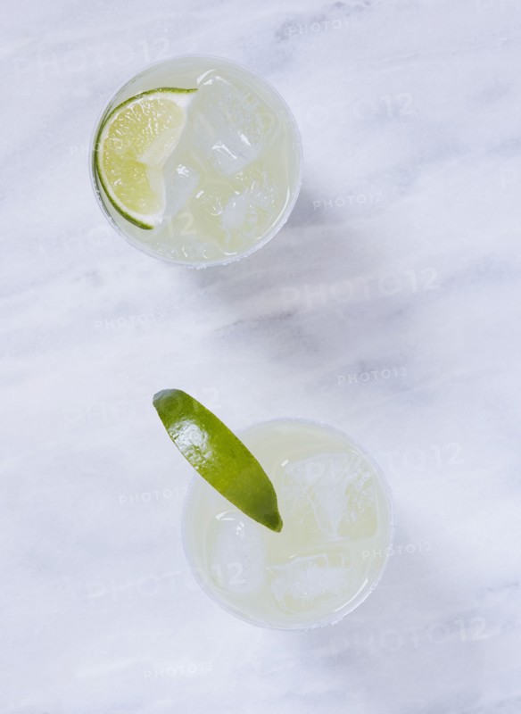 Overhead view of two margaritas on marble table