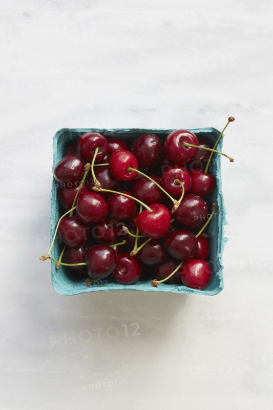 Overhead view of cherries in blue fruit carton