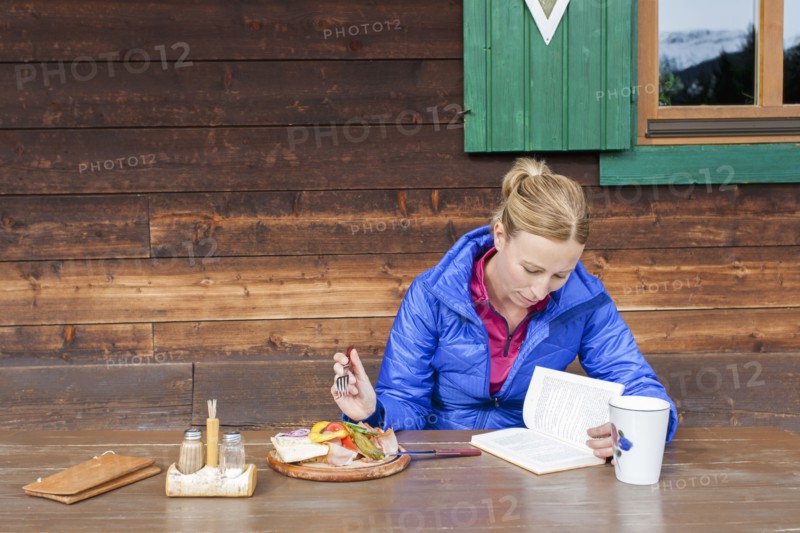 Austria, Salzburger Land, Maria Alm, Mature woman reading book during lunch
