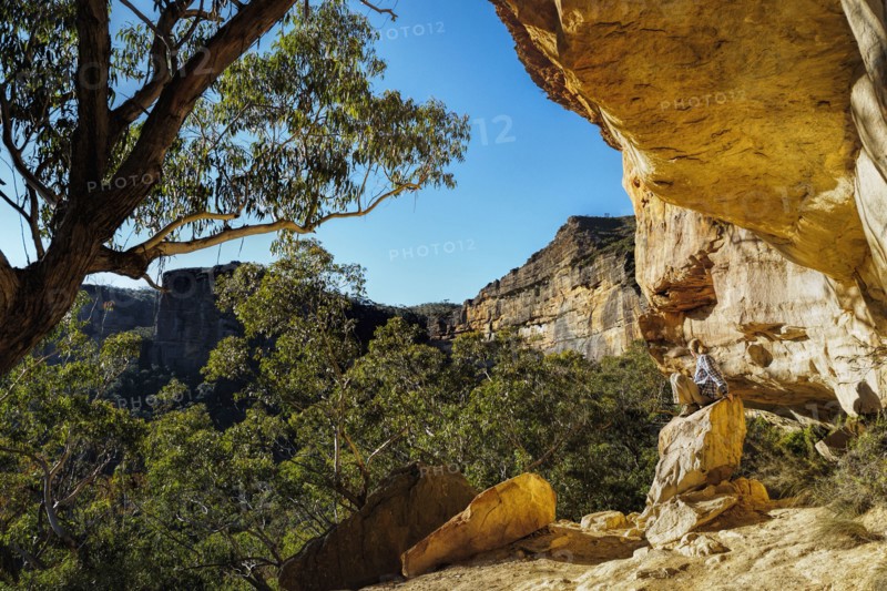 Australia, New South Wales, Blue Mountains, Mature woman resting on rock under cliff in mountain forest