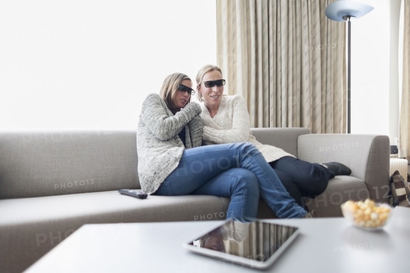 Women in 3d glasses sitting on sofa in living room