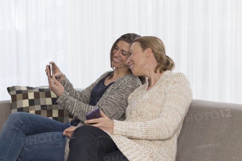 Women sitting on sofa and looking at phone