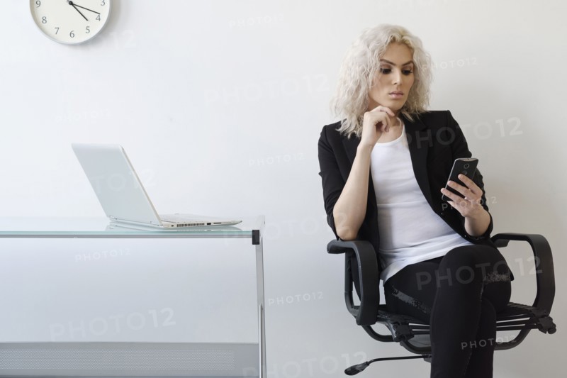 Young businesswoman using phone in office.