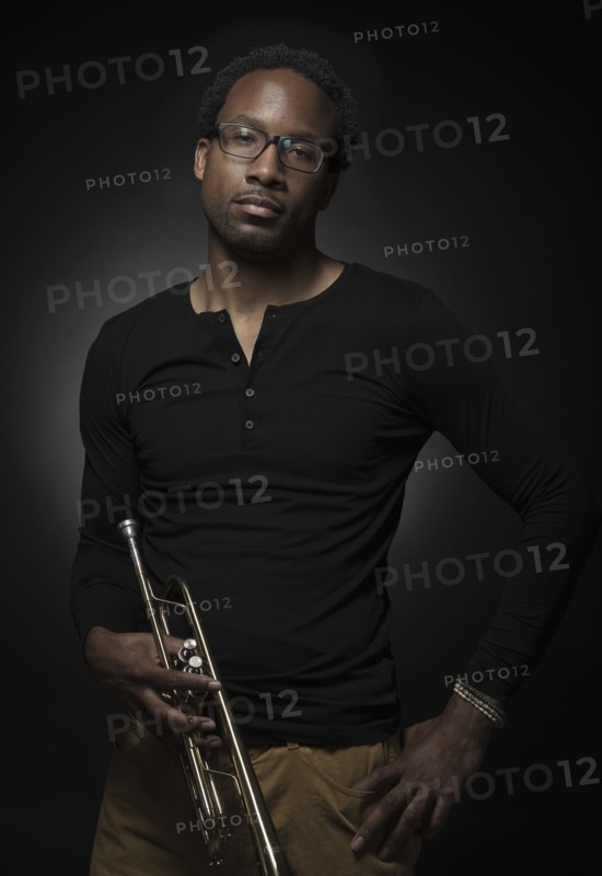 Studio portrait of mid adult man holding trumpet.