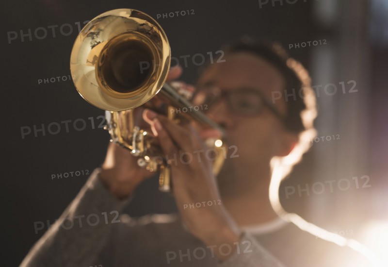 Mid adult man playing trumpet.