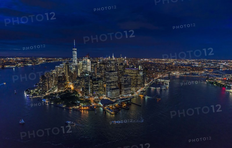 USA, New York, New York City, Manhattan, Aerial view of illuminated skyline with harbor at night.