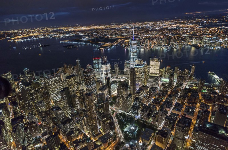 USA, New York, New York City, Manhattan, Aerial view of illuminated skyline with harbor at night.