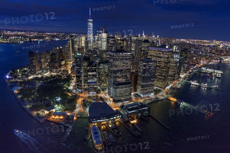 USA, New York, New York City, Manhattan, Aerial view of illuminated skyline with harbor at night.