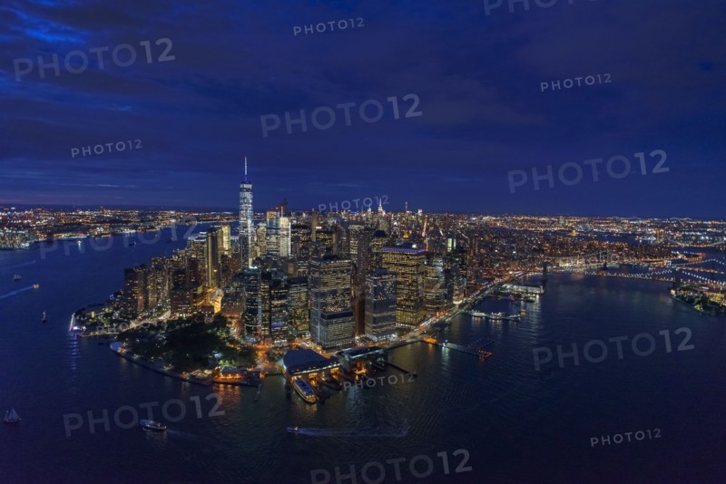 USA, New York, New York City, Manhattan, Aerial view of illuminated skyline with harbor at night.