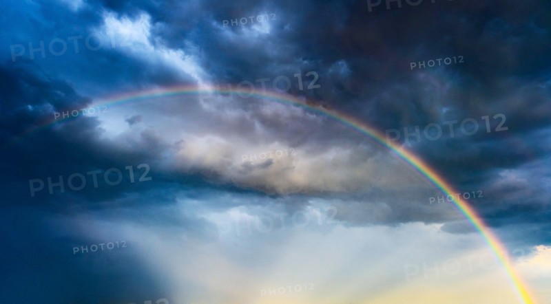 Rainbow against dramatic sky at sunset.