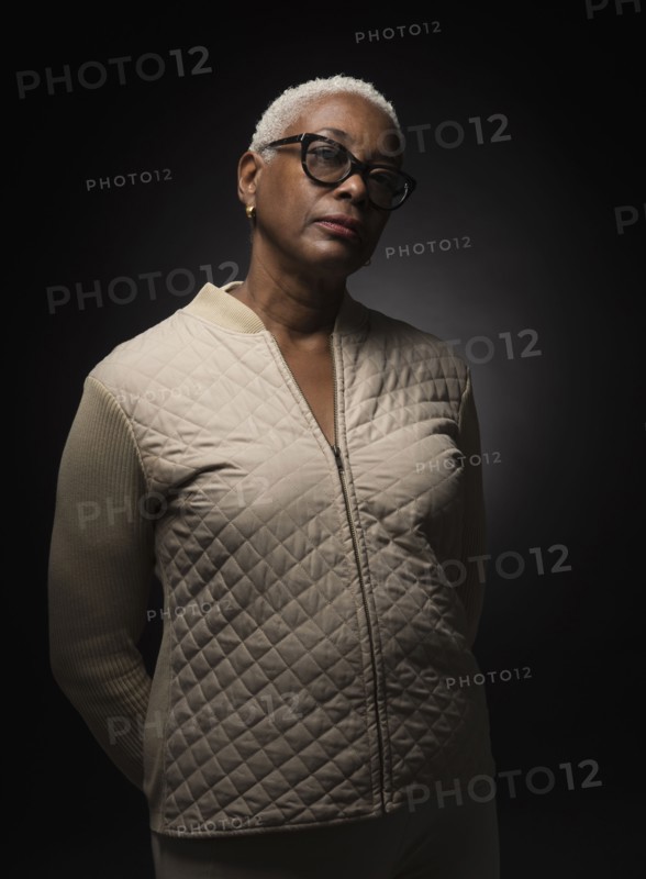 Studio shot of woman standing with hands behind back.