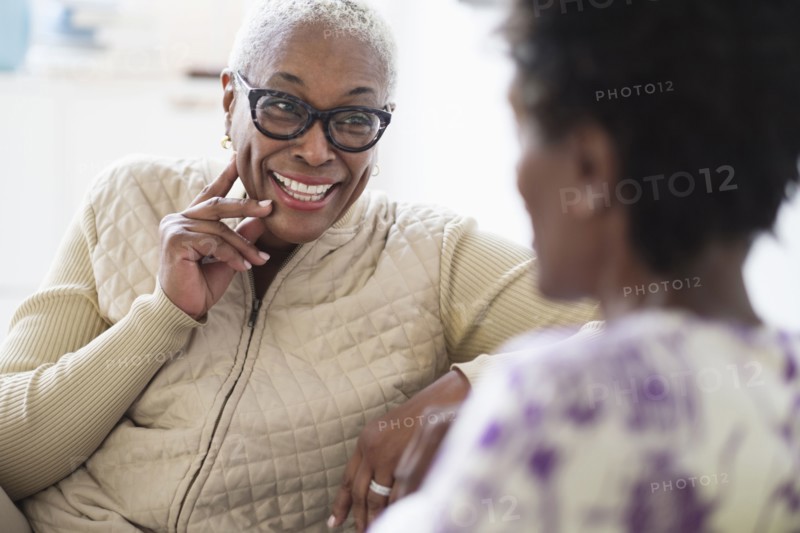 Smiling women sitting and talking in living room.