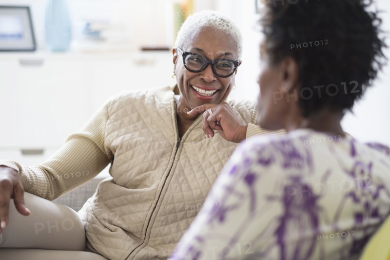Smiling women sitting and talking in living room.