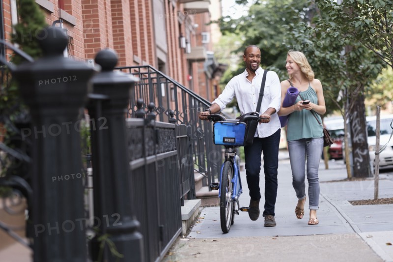 Couple walking with bicycle and exercising mat.