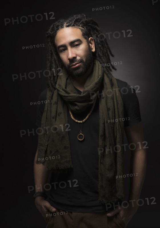 Portrait of man with dreadlocks on black background.