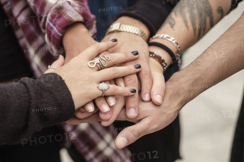 Stack of hands, friends holding hands outdoors.