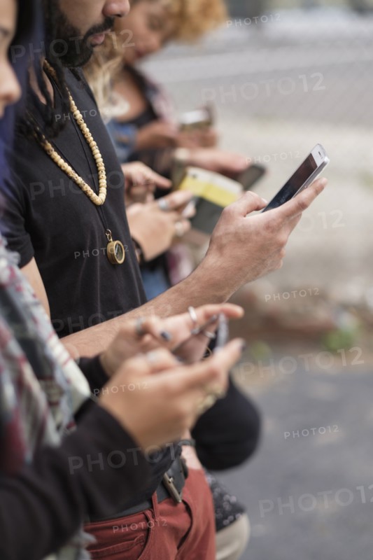 Young people standing in row using smartphones.