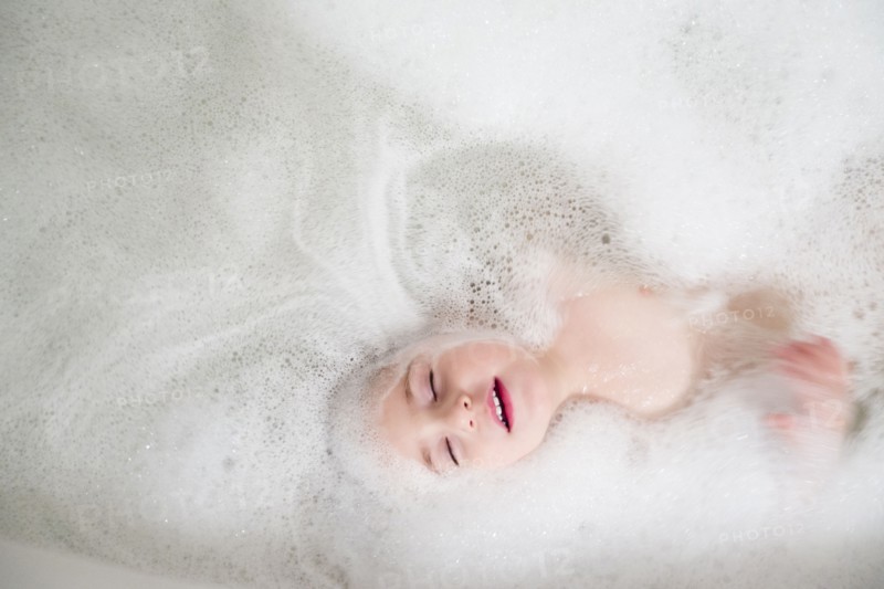 Girl (2-3) lying in bathtub