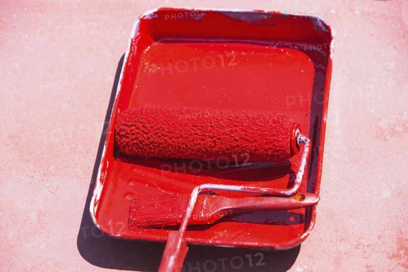 Paint roller in tray with red paint