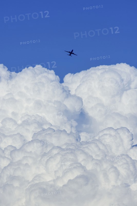 Airplane flying over large cloud