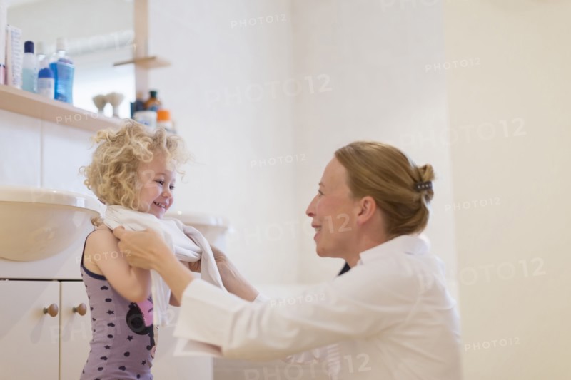 Mother helping daughter (4-5) get dressed