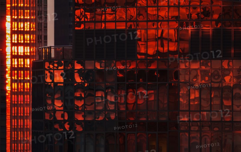 USA, New York State, New York City, Reflection on glass facade of office building at sunset.