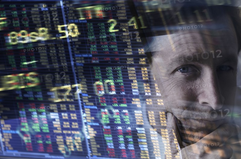 Face of mature man among stock exchange charts and numbers.